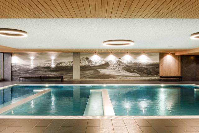 Hallenbad-Visualisierung mit Holzdecke und beleuchtetem Bergmotiv